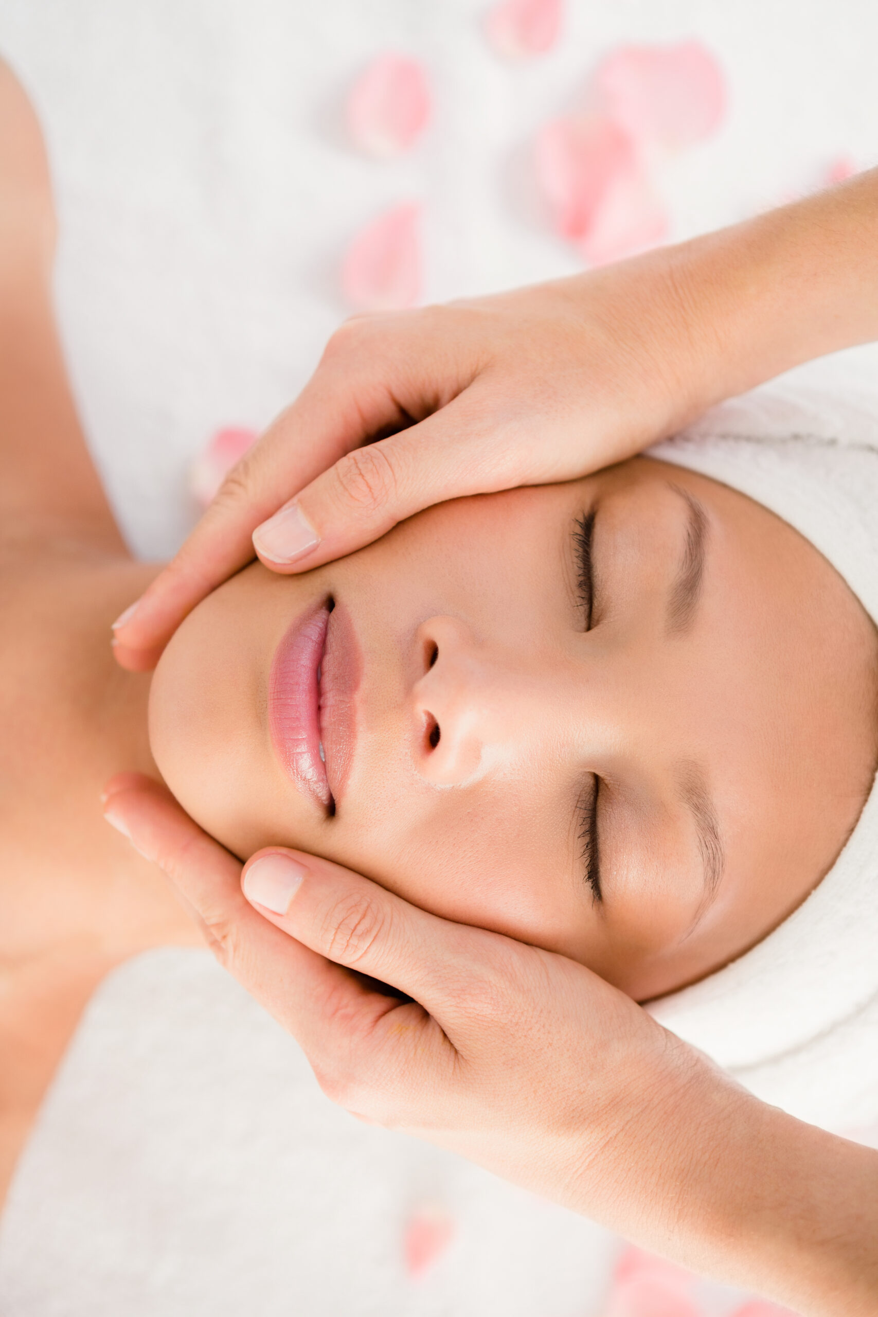 Upward view of an attractive young woman receiving facial massage at spa center